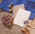 Red wine cork heart, white and craft paper sheets, blue flower on rustic sackcloth background. Design template for greeting card, Royalty Free Stock Photo