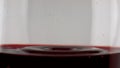 Red wine dripping glass closeup. Smooth grape liquid surface rippling in circles