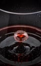 Red wine drop splashing inside glass close up