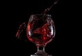 Red wine falls into a glass and creates splash and splashes on a black background