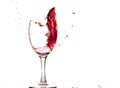 Red wine falls into a glass and creates splash and splashes on a white background