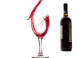 Red wine falls into a glass and creates splash and splashes on a white background