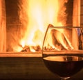 Two Glasses of red wine on cozy fireplace background, close up.