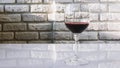 Red wine in a glass against a brick wall background,close-up,an alcoholic drink made from grapes. Royalty Free Stock Photo