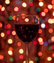 Red wine glass against christmas lights bokeh background Royalty Free Stock Photo