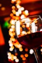 Red wine glass against christmas lights decoration background