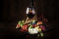 Red wine glass and appetizers, cheese, salami, figs, grapes, vintage wooden table background, selective focus, copy space Royalty Free Stock Photo