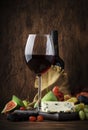 Red wine glass and appetizers, cheese, salami, figs, grapes, vintage wooden table background, selective focus, copy space Royalty Free Stock Photo