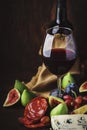 Red wine glass and appetizers, cheese, salami, figs, grapes, vintage wooden table background, selective focus, copy space