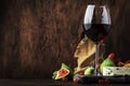 Red wine glass and appetizers, cheese, salami, figs, grapes, vintage wooden table background, selective focus, copy space