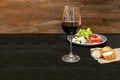 Red wine in glass, bottle, brie, blue cheese, grapes, jamon meat, salami on black slate board on wooden table, alcohol Royalty Free Stock Photo