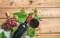 Red wine glass and bottle and fresh grapes on wooden background, copy space Royalty Free Stock Photo