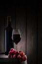 Red wine in glass and bottle standing on barrel with bunch of grapes Royalty Free Stock Photo