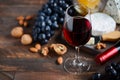 Red wine glass with cheese, grapes, honey and nuts on a wooden table. Royalty Free Stock Photo