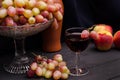 Red wine in a glass with grapes in a vase on a wooden table on a black cloth background with an old bottle. For wine advertising Royalty Free Stock Photo