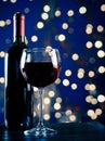 Red wine glass near bottle with light blue bokeh Royalty Free Stock Photo