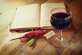 Red wine glass and old book on wooden table at sunset burst. vintage filtered image Royalty Free Stock Photo