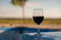 Red wine glass sitting on pool side Royalty Free Stock Photo