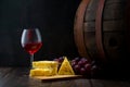 Red wine in low light with cheese and grape,wine barrel and glass