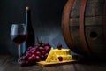 Red wine in low light with cheese and grape,wine barrel and glass