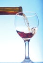 Red wine poured from a bottle into a transparent glass glass. Royalty Free Stock Photo