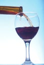 Red wine poured from a bottle into a transparent glass glass. Royalty Free Stock Photo