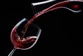 Red wine is poured into a wine glass on a black background Royalty Free Stock Photo