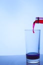 Red wine is poured into a glass glass with blue liquid Royalty Free Stock Photo