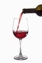 Red wine is poured into a glass from a bottle, isolate on a white background. Royalty Free Stock Photo