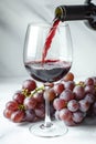 Red wine poured into glass, grapes on white background. AI Generated Royalty Free Stock Photo