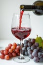 Red wine poured into glass and grapes on white background. AI Generated Royalty Free Stock Photo