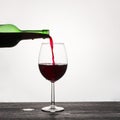 Red wine is poured from a glass green bottle into a glass on a white background Royalty Free Stock Photo