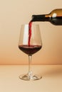 Red wine poured into glass, isolated on beige background. AI Generated Royalty Free Stock Photo