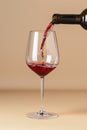 Red wine poured into glass, isolated on beige background. AI Generated Royalty Free Stock Photo