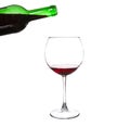 Red wine pouring from bottle into big glass on white Royalty Free Stock Photo