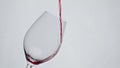 Red wine pouring glass closeup slow motion. Alcoholic liquid filling goblet