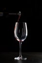 Red wine pouring into a glass with drops on black background Royalty Free Stock Photo