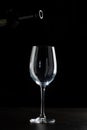 Red wine pouring into a glass with drops on black background Royalty Free Stock Photo