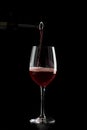 Red wine pouring into a glass with drops on black background Royalty Free Stock Photo