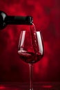 Red wine pouring in glass on red background. Glass of wine with bottle. Drink for celebrating, date, family dinner, party. Wine Royalty Free Stock Photo