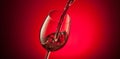 Red wine pouring into a glass on red background Royalty Free Stock Photo