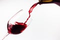 Red wine pouring in the glass on white background. Wine glass, bottle and splashes of red wine Royalty Free Stock Photo