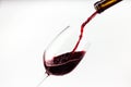 Red wine pouring in the glass on white background. Wine glass, bottle and splashes of red wine Royalty Free Stock Photo