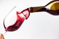 Red wine pouring in the glass on white background. Wine glass, bottle and splashes of red wine Royalty Free Stock Photo