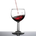 Red wine pouring, slanted horizon. White background.