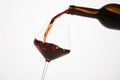 Red wine pouring into tilted wineglass from bottle. Royalty Free Stock Photo