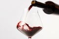 Red wine pouring into tilted wineglass from bottle. Royalty Free Stock Photo