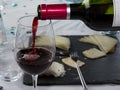 Red wine pouring into wine glass, with cheese . Royalty Free Stock Photo