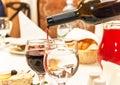 Red wine pouring into wine glass, that standing on the table. Royalty Free Stock Photo