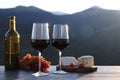 Red wine served with cheese and grapes on wooden table against mountain landscape Royalty Free Stock Photo